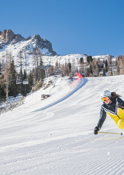 Skier downhill Pra di Tori slope in the background Latemar | © Carezza Dolomites/Harald Wisthaler