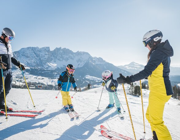 Family skiing with a view of snow-covered Latemar | © Carezza Dolomites/Harald Wisthaler